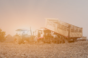 Fototapeta premium Dump truck with tractor dumping gravel on an excavation site