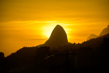 Silhouette of Two Brothers (Dois Irmaos) Mountain on the background of gold sunset from Copacabana beach, Rio de Janeiro, Brazil