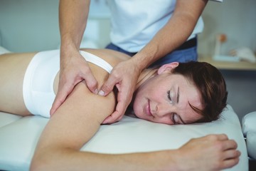 Obraz na płótnie Canvas Physiotherapist giving shoulder massage to a woman