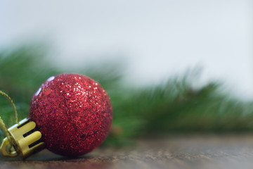 red Christmas ball on a wooden board with Christmas tree branch