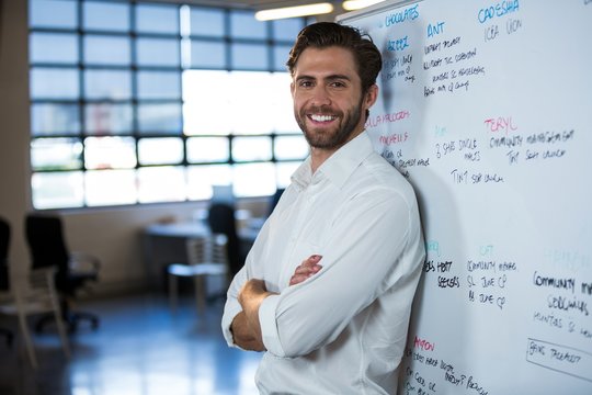 Confident businessman leaning on whiteboard