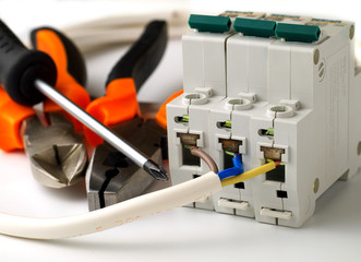 set of electrician tools and equipment and a coil of wire on a white background, focus on cutter