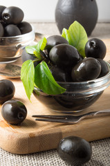 Black olives in a glass bowl decorated with green leaves