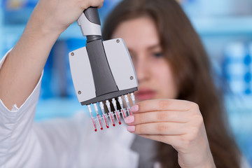Young woman in biological laboratory. Attractive young female scientis.Young scientist pipetting...
