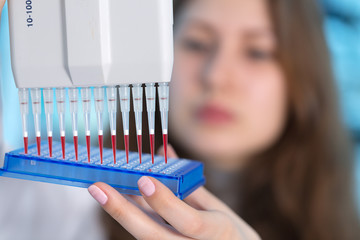 Young woman in biological laboratory. Attractive young female scientis.Young scientist pipetting...