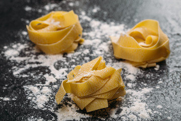 Uncooked rolled traditional italian pasta. Portion of raw fettuccine or tagliatelle or pappardelle. Dry pasta from whole wheat flour. Ingredients for tasty dish