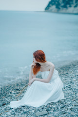 Fototapeta na wymiar Woman on the beach in a white dress