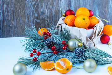 Christmas composition with tangerines, cinnamon and fir twigs in wooden plate on a festive table on a green background with snowflakes and cones fake.tinted