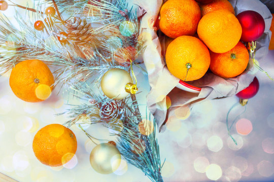 Christmas composition with tangerines, cinnamon and fir twigs in wooden plate on a festive table on a green background with snowflakes and cones fake.tinted