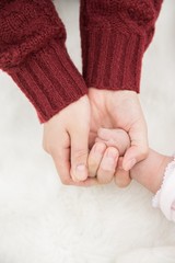 赤ちゃんの手を握る母親の手