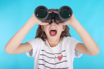 Beautiful young girl  looking through binoculars with surprised expression