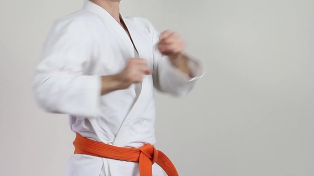 Athlete with a red belt on a light background makes the punch