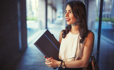 Beautiful businesswoman outdoors holding folders