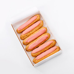 Open delivery paper box with six fresh pink cupcakes on white background. Top view. Unhealthy or dieting concept.