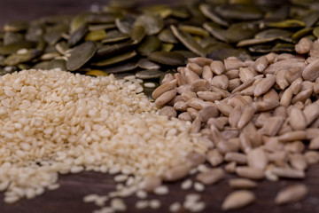 Sesame, pumpkin and sunflower seeds on wooden background