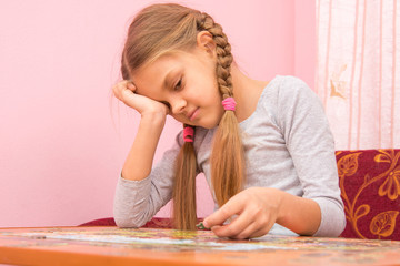 Girl little tired collecting picture of puzzles