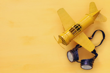 Top view of vintage yellow toy plane and pilot glasses