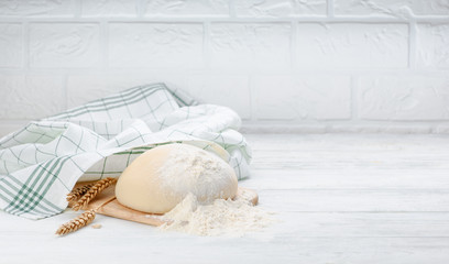 Ball of raw dough isolated on white wooden table with ears wheat and napkin. Copy space.
