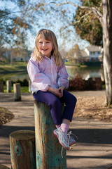 Young girl sitting on a post by the dock