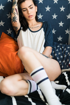 Tattooed female in shirt on bed