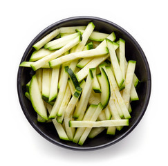 Bowl of fresh zucchini slices isolated on white, from above