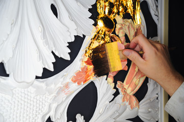Ein Vergolder schiesst Blattgold mit dem Pinsel an