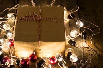 Gift box on a wooden background surround by Christmas light bulb and christmas balls