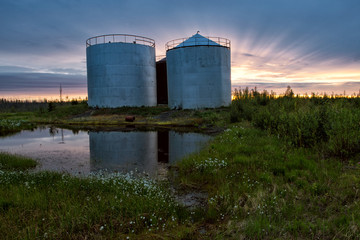 Fototapeta na wymiar Large tanks at sunset sky background. Indigirka shore. Yakutia. Russia.