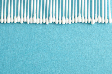 A row of cotton swabs isolated on a light blue background