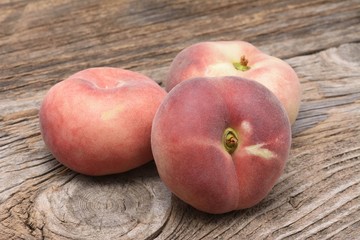 Dough nut peaches also known as Saturn peach on wooden board
