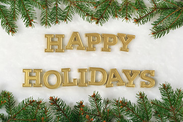 Happy holidays golden text and spruce branch on a white