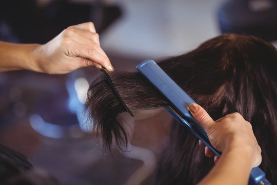 Hairdresser straightening the hair of a client