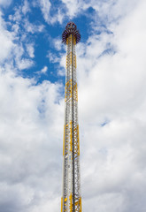 High free fall tower in an amusement park with blue sky and clou