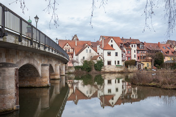 Fototapeta na wymiar Small German village seen next to a bridge with its reflection i
