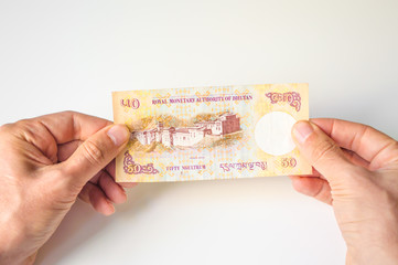 Man holding fifty Bhutanese Ngultrum banknote in his hands