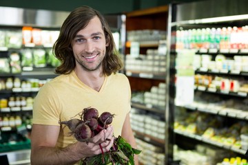 Man holding bunch of beetroots in supermarket