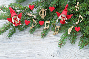 Musical notes, angel ,  instruments on christmas tree brunch on wooden background 