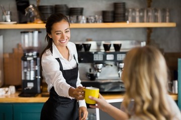 Waitress offering a cup of coffee - obrazy, fototapety, plakaty