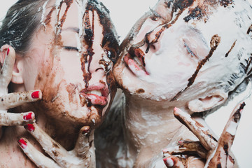 two girls doused with white and dark chocolate. passionate women