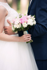 the groom and the bride hold a wedding bouquet of pink and white peonies in hand. Wedding day. Newlyweds