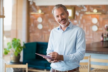 Portrait of smiling man writing in a file