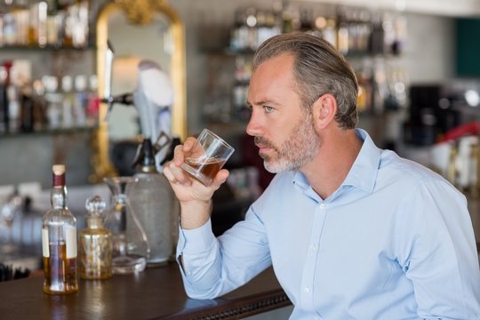 Serious Man Drinking Whiskey At Bar Counter