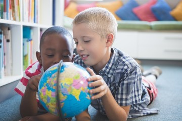 School kids studying globe in library