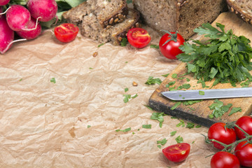 Kitchen background with baking paper, tomatoes, radish and parsley