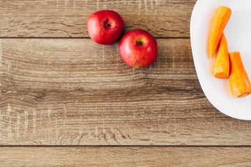 red apple and yellow carrots on the wooden table