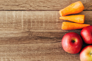 red apple and yellow carrots on the wooden table