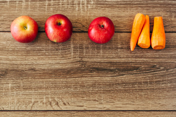 red apple and yellow carrots on the wooden table