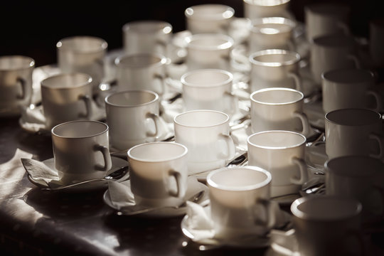 Closeup image of white cups at blurred table background.