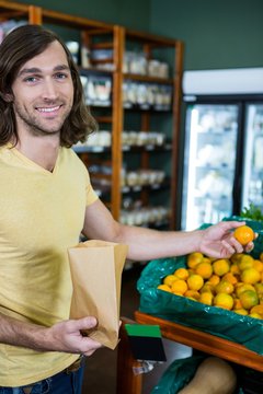 Portrait of smiling man selecting oranges in organic section