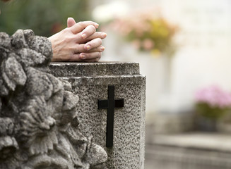 Hands of a praying woman in cemetery